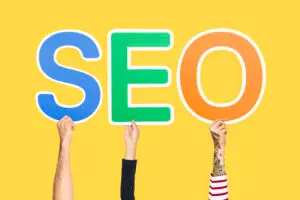 Hands holding colorful SEO letters against yellow background